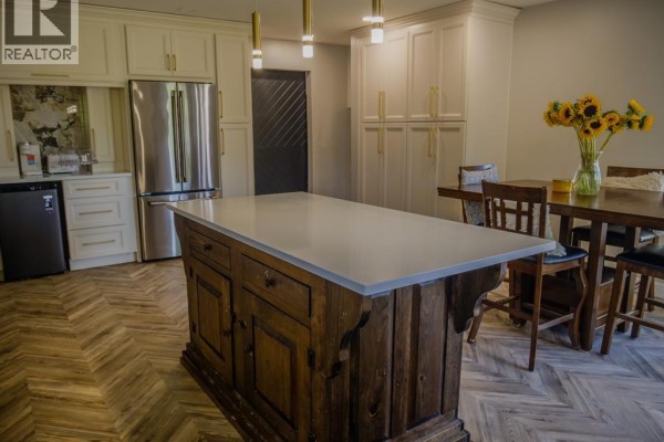 Kitchen with island, stainless steel fridge, and dining table - 94 Ottawa Drive Chatham