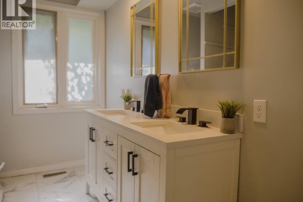 Double vanity with black faucets and gold mirrors - 94 Ottawa Drive Chatham