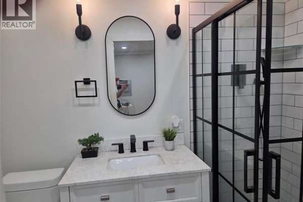 Modern bathroom vanity, sink, mirror, and black-framed glass shower - 94 Ottawa Drive Chatham