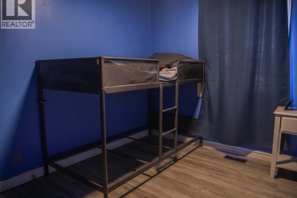 Bunk bed in bedroom with blue walls and wood-look flooring - 94 Ottawa Drive Chatham