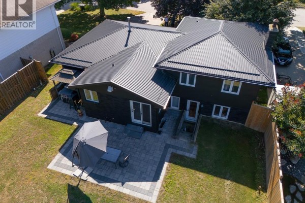 Rear view of the home showing a two-story section with multiple windows and a large black metal roof. - 94 Ottawa Drive, Chatham
