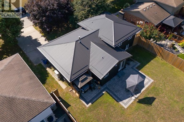 Aerial perspective of the property with a large black metal roof, fenced backyard, patio, and surrounding homes. - 94 Ottawa Drive, Chatham