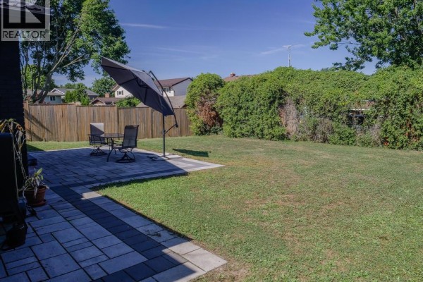Paved patio with furniture and umbrella in backyard - 94 Ottawa Drive Chatham