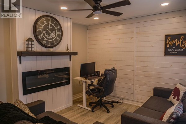 Living room with electric fireplace, large clock, desk, and sofa - 94 Ottawa Drive Chatham