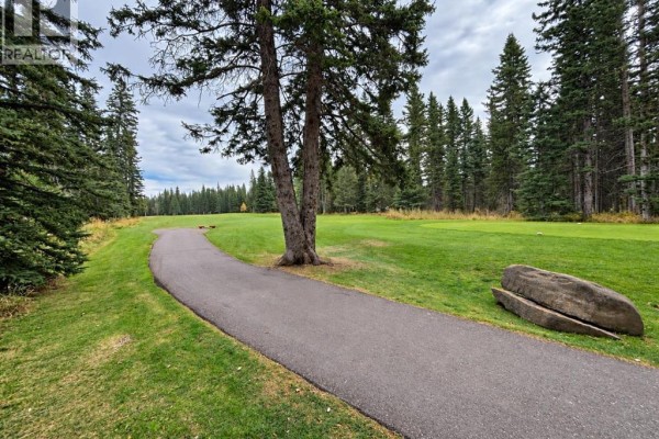 A spacious kitchen with light wood cabinets, stainless steel appliances, and tile flooring. - 94 Redwood Meadows Drive, Rural Rocky View County