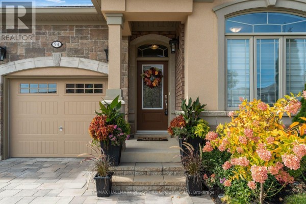 Close-up of the front entrance with a glass-paneled door, wreath, and potted plants. - 94 Summerhill Drive, New Tecumseth