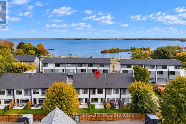 Aerial view of townhouses with backyards and a large blue lake in the background. - 94 Sunshine Lane, Orillia