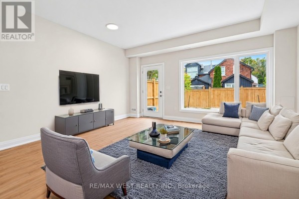 Living room with a sectional sofa, armchair, coffee table, television, and large window. - 94 Sunshine Lane, Orillia