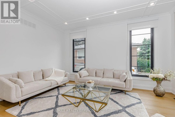 Living room with two beige sofas, a glass coffee table, and large windows with black frames. - 94 Vista Boulevard, Mississauga
