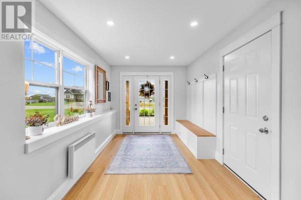 Bright entryway with light wood floors, white walls, large windows, and built-in bench. - 94 Water's Edge Lane, Cornwall