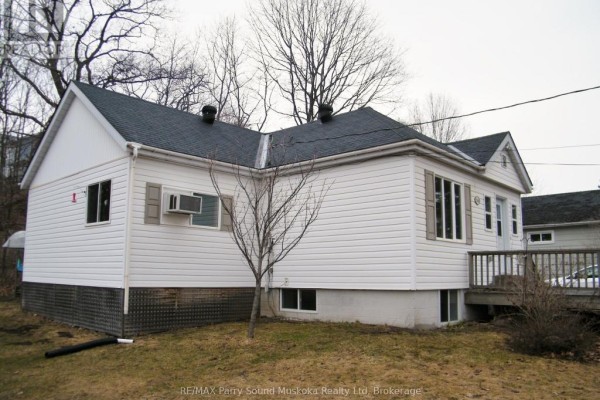 Side view of white vinyl-sided house with dark roof and wooden deck. - 94 William Street, Parry Sound