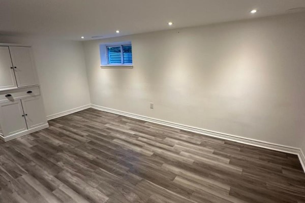 Empty room with gray wood-look flooring, white walls, and a white storage cabinet. - 94 Wright Street, Richmond Hill