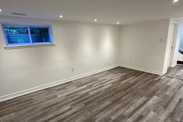 Empty room with gray wood-look flooring, white walls, and a window to the outside. - 94 Wright Street, Richmond Hill