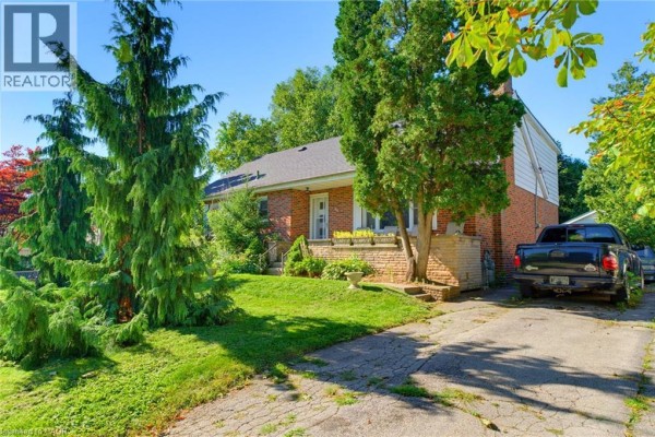 Side view of a brick house with a driveway and a pickup truck. - 940 Harvey Place, Halton