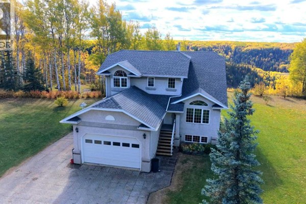 Front exterior of a gray stucco house with a double garage, dormer windows, and a sloped roof. - 94038b -- 702 Township, Rural Grande Prairie No  1, County Of