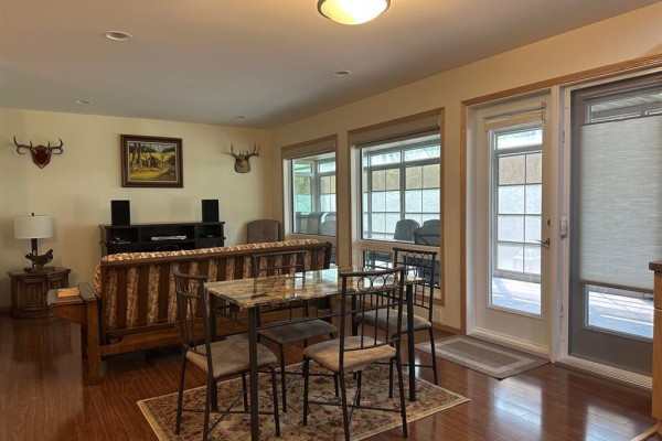 Living area with a sofa, entertainment center, and a small marble-topped dining table. - 94067 Wilson Road, Shoal Lake