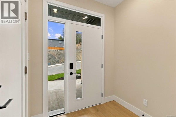 Front entrance with a white door, sidelights, and a black door handle. View of the street outside. - 941 Malbec Link, Langford