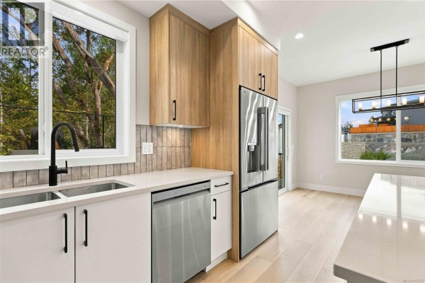 Kitchen with white countertops, light wood cabinets, stainless steel appliances, and a black faucet over the sink. - 941 Malbec Link, Langford