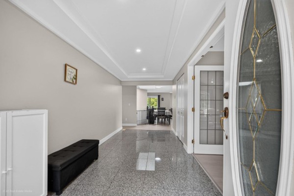 Entrance hall with gray speckled tile floors, a black bench, and double entry doors. - 9416 163a Street, Surrey