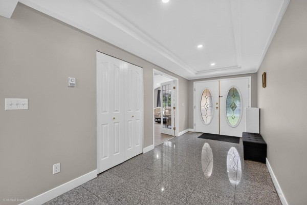 Entrance hall with gray speckled tile floors, white double doors, and a bench. - 9416 163a Street, Surrey