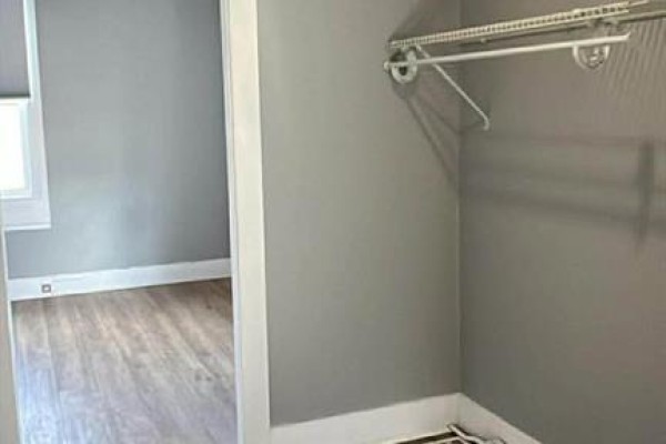 Interior view of a closet with a shelf and hanging rod against grey walls. - 9418 Main, Richibucto