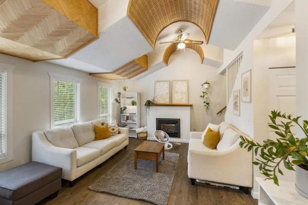 Living room with vaulted ceiling, white sofas, fireplace, coffee table, and artwork. - 9418 Mcnaught Road, Chilliwack Proper East, Chilliwack