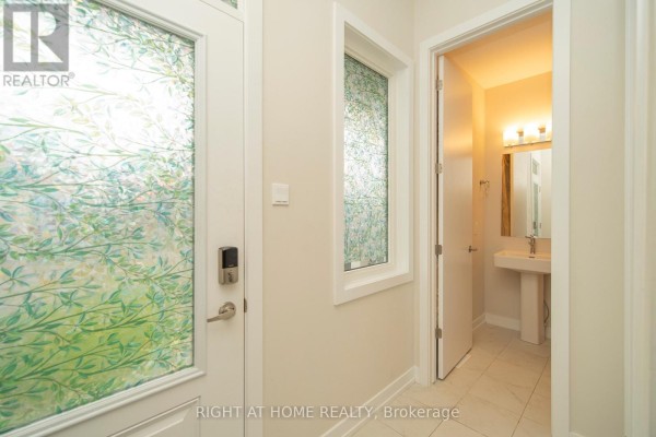 Close-up of the front door with frosted glass panels and a digital lock, adjacent to a small bathroom. - 942 Seagrave Lane, Ottawa