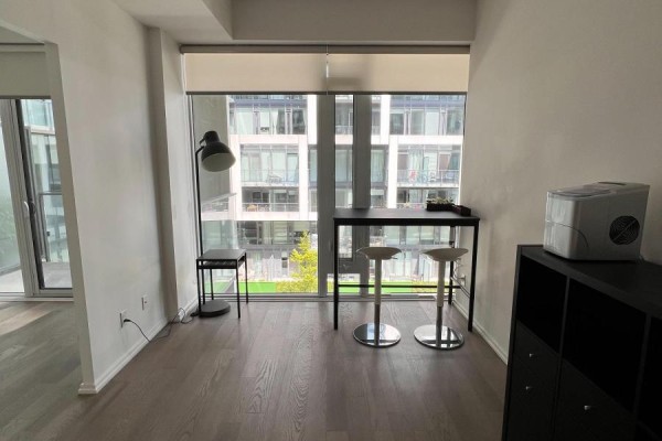 Living area with floor-to-ceiling window, high table, stools and floor lamp. - 943 - 8 Hillsdale Avenue E, Toronto
