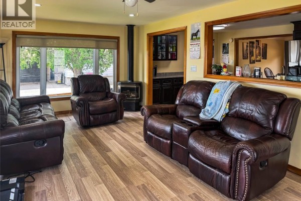 Living room with brown leather reclining sofas, a wood-burning stove, and wood laminate flooring. - 944 Mcnaughton Avenue, Chatham