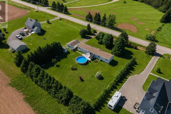 Aerial view of 945 Newton Road property showing a white mobile home, garage, and barn. - 945 Newton Road, Kinkora