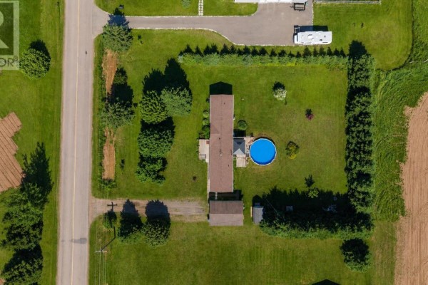 Exterior view of a light-colored mobile home with a wooden deck and attached garage. - 945 Newton Road, Kinkora