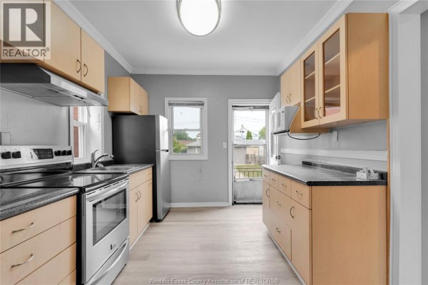A bathroom vanity with a white sink, black faucet, and white cabinet, with a black framed mirror above. - 946 Howard Avenue Unit# 1 & 2, Windsor