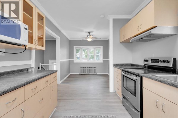 A bathroom with a white toilet, black toilet paper holder, and a modern vanity with a white sink. - 946 Howard Avenue Unit# 1 & 2, Windsor