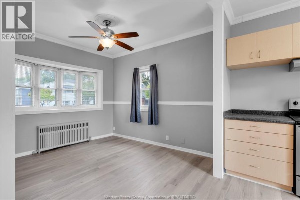 A combined living and kitchen area with light wood floors, grey walls, and a stainless steel refrigerator. - 946 Howard Avenue Unit# 1 & 2, Windsor