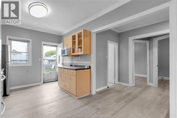 A modern white kitchen with quartz countertops, black hardware on cabinets, and a black faucet over a sink. - 946 Howard Avenue Unit# 1 & 2, Windsor