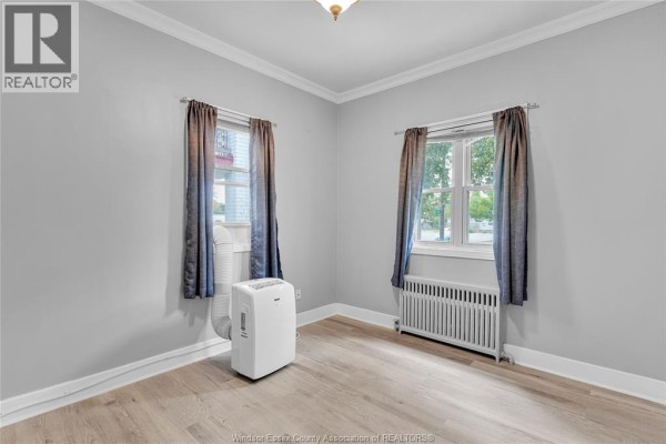 Living area and kitchen with stainless steel appliances, white cabinets, and light wood floors. - 946 Howard Avenue Unit# 1&2, Windsor