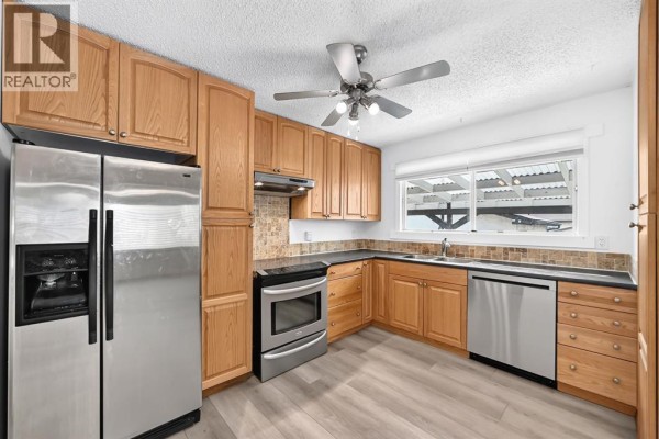 Kitchen with light oak cabinets, stainless steel appliances, and a window view. - 947 Maitland Way Ne, Calgary
