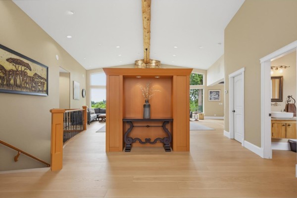 Interior hallway with light wood floors, a decorative wooden console table, and doorways to other rooms. - 9472 222 Street, Langley