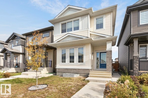 Exterior front view of a two-story house with beige siding and stone accents. - 9478 Colak Ln Sw Sw, Edmonton