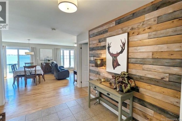 Interior hallway with a wood-plank accent wall and a console table, leading to a dining and living area. - 948 Rue Des Chalets Street, Tracadie