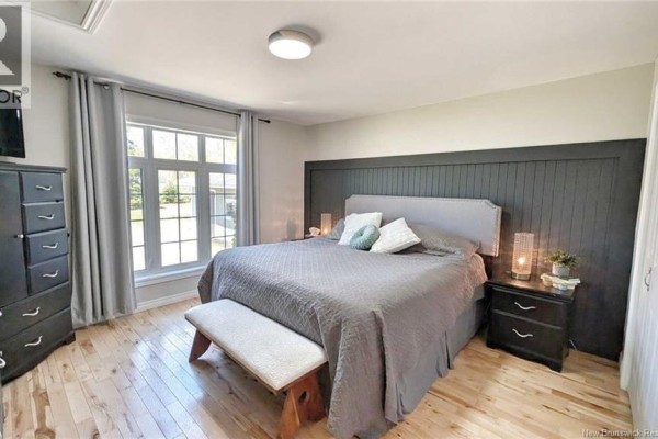Bedroom with a king-size bed, grey bedding, wood floors, a window, and dark wood furniture. - 948 Rue Des Chalets Street, Tracadie