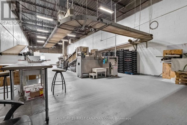 Interior view of a commercial kitchen with machinery, shelving units, and industrial lighting. - 95 Bessemer Road, London South