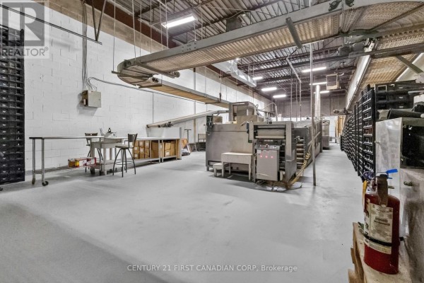 Commercial kitchen space with stainless steel equipment, conveyor systems, and black storage racks. - 95 Bessemer Road, London South