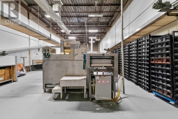 Commercial kitchen setting with large stainless steel equipment and rows of storage shelves. - 95 Bessemer Road, London South
