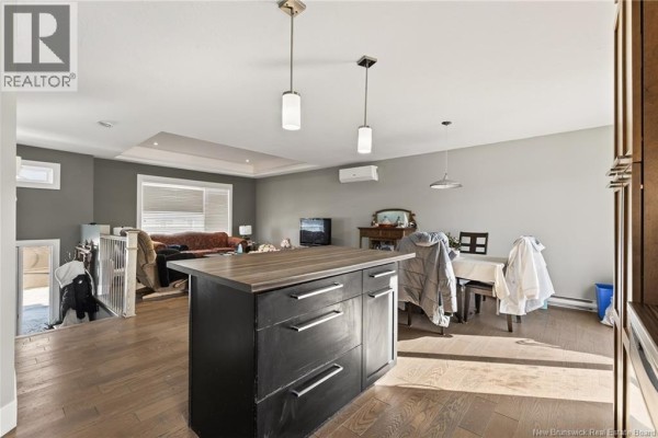 Modern kitchen featuring dark wood cabinets, stainless steel appliances, and an island with seating. - 95 Doiron Street, Dieppe