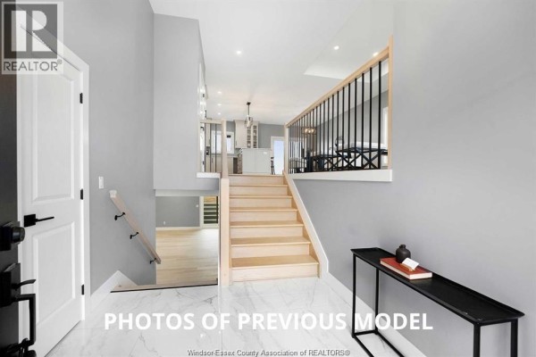 Foyer and staircase view looking towards the living area and kitchen with beige walls and tile floor. - 95 Fenceline Drive, Chatham