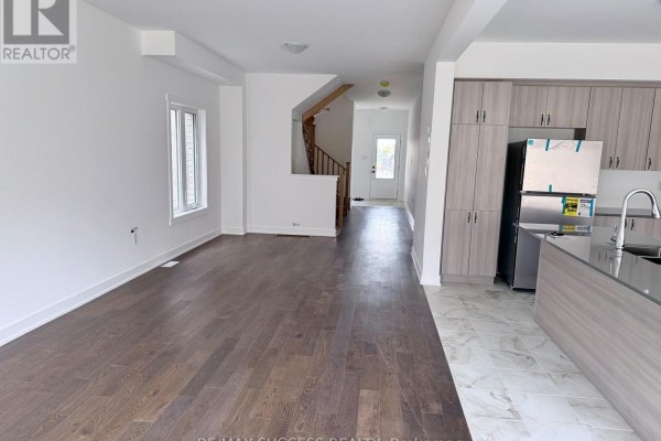 Open-concept living area with dark hardwood floors, white walls, and a staircase leading upstairs. - 95 Flan Boulevard, Barrie