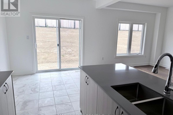 Kitchen island with a sink, overlooking a tiled area with a sliding glass door to the backyard. - 95 Flan Boulevard, Barrie