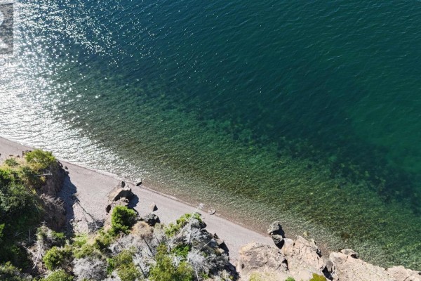 Overhead view of a rocky shoreline and clear green water with sunlight sparkling. - 95 Lakeshore Drive W, Irish Cove