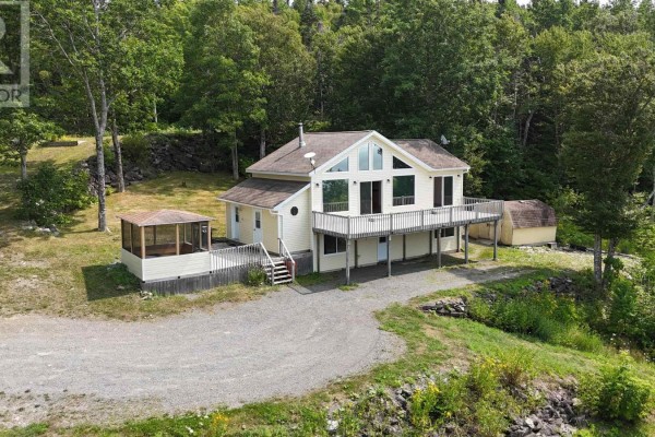 Yellow house with a wrap-around deck, screened porch, and attached shed surrounded by trees. - 95 Lakeshore Drive W, Irish Cove
